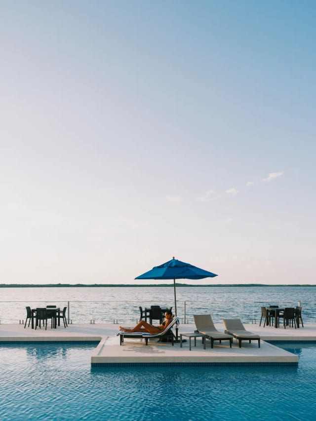Waterfront pool deck and blue umbrella at Sunset Caribe