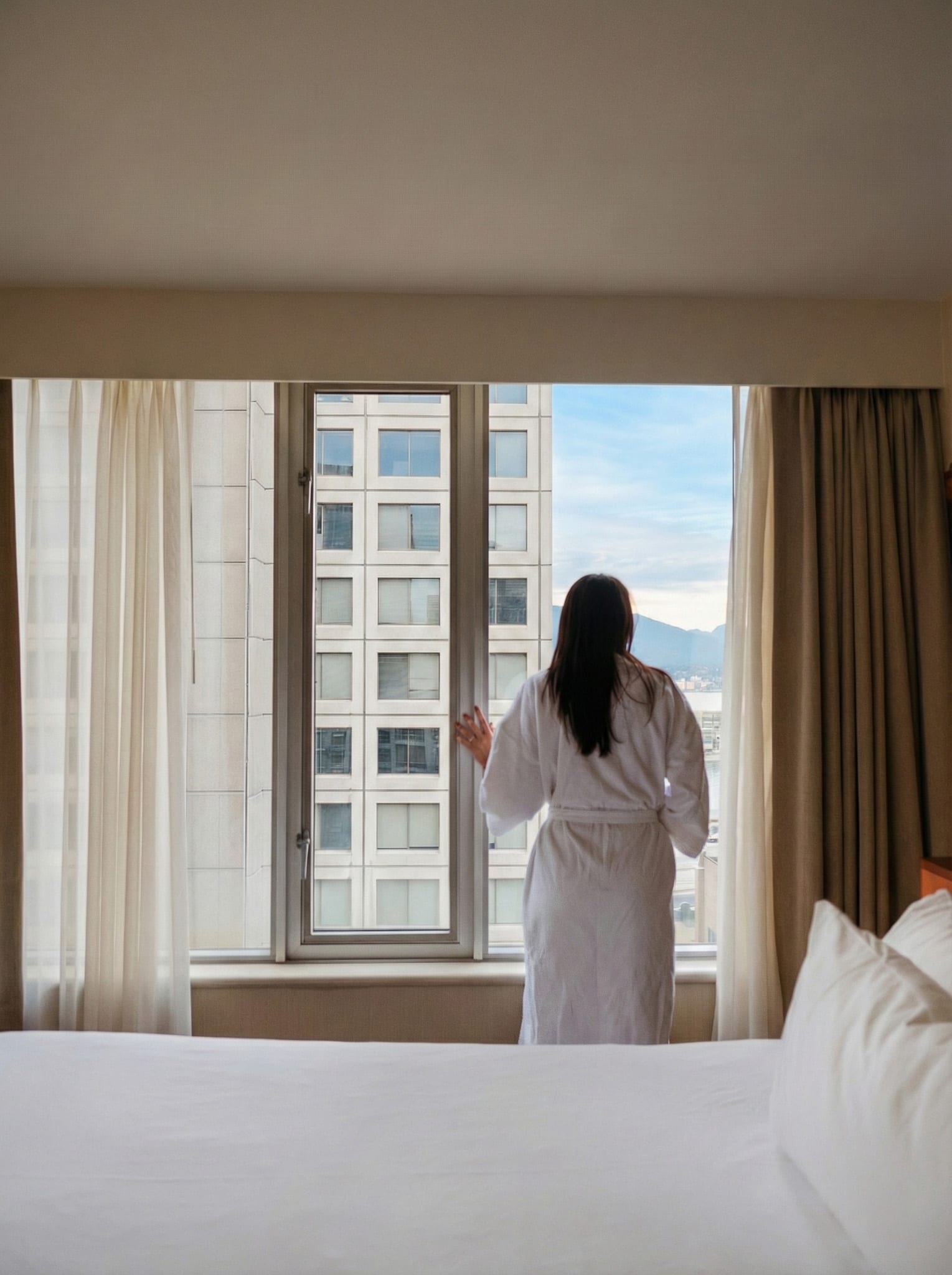 Guest standing at the window in a Delta Downtown room