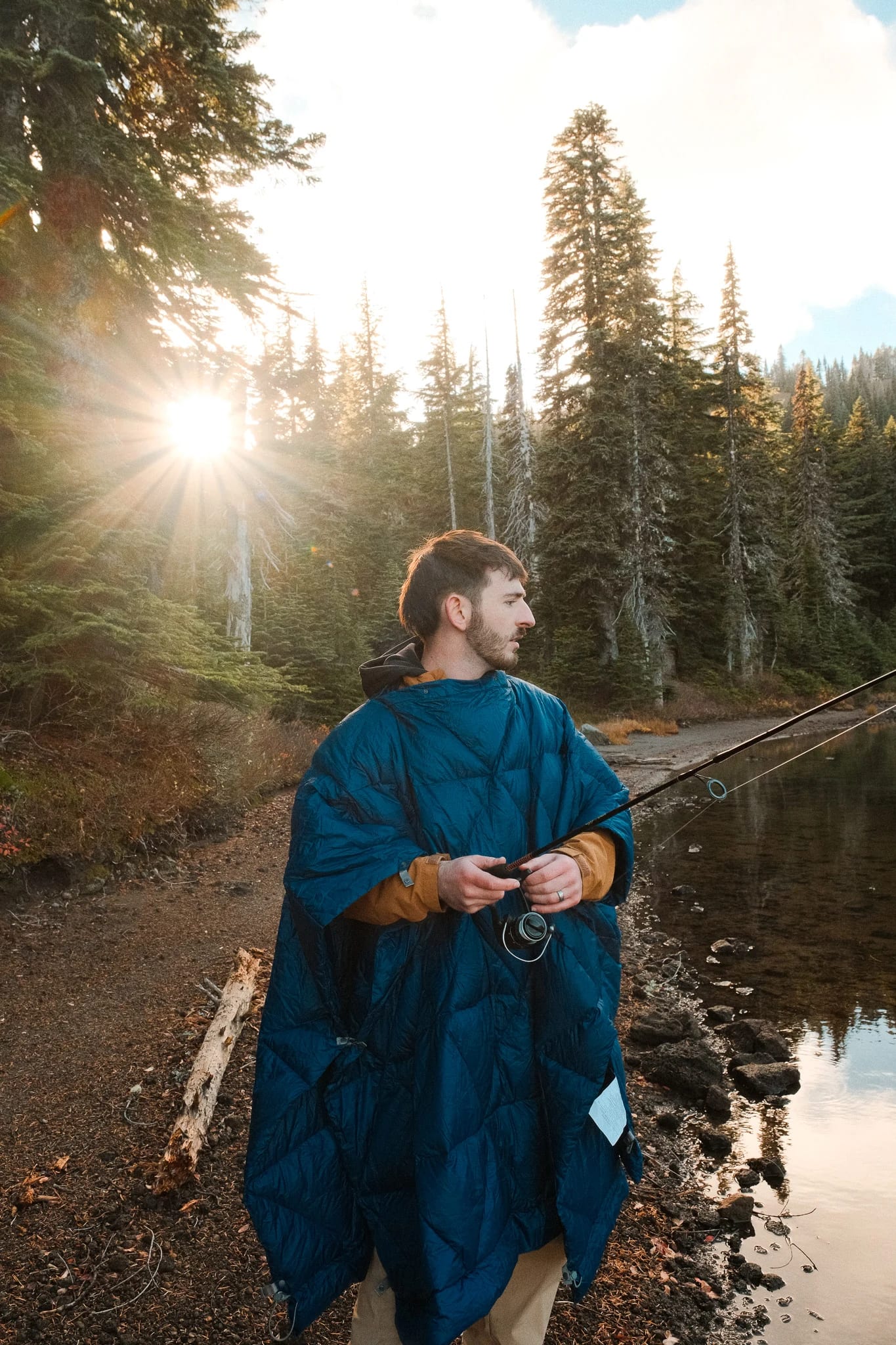 Camper wrapped in a blue blanket beside the lake