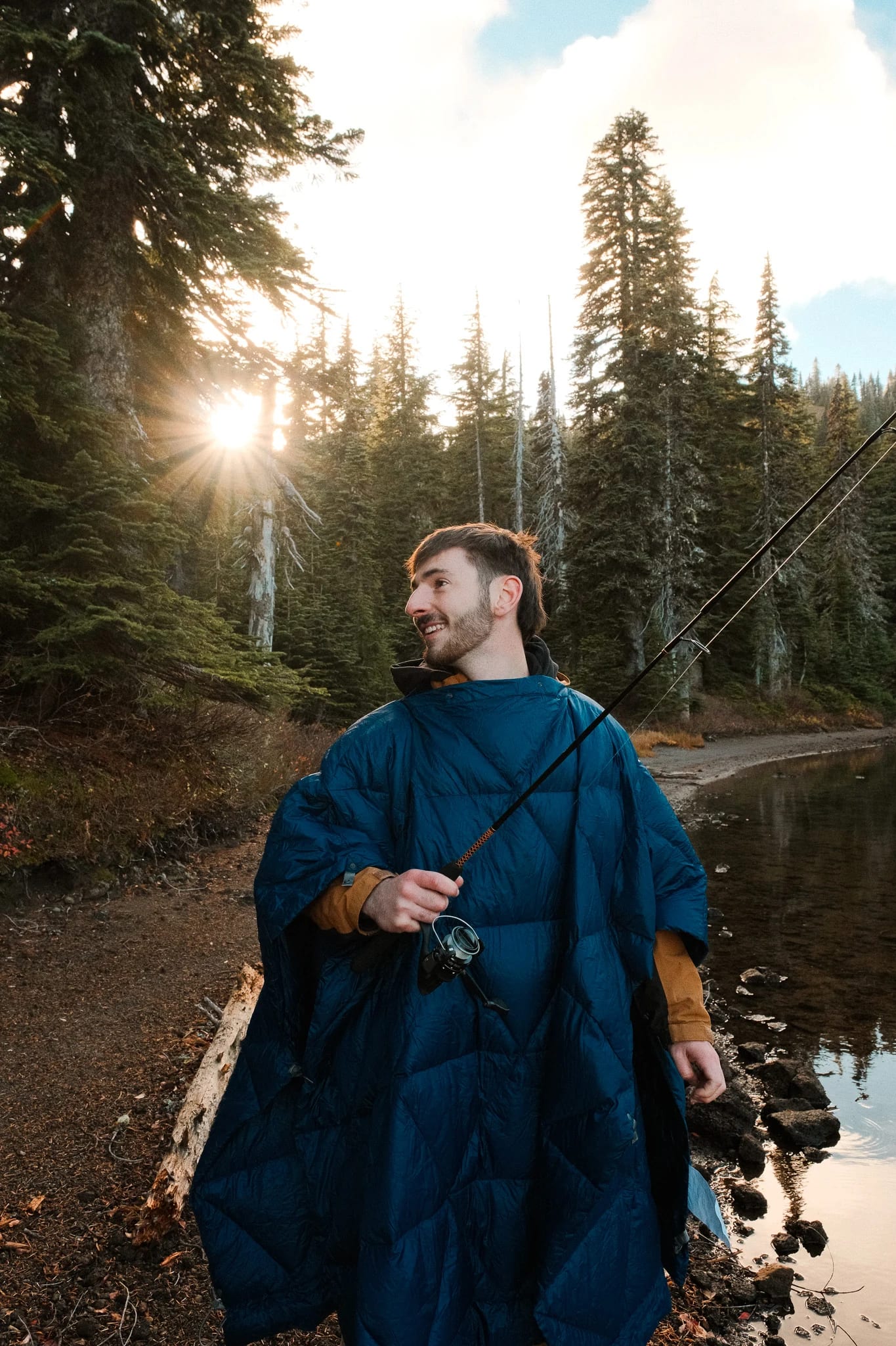 Camper wrapped in a blue blanket beside the lake