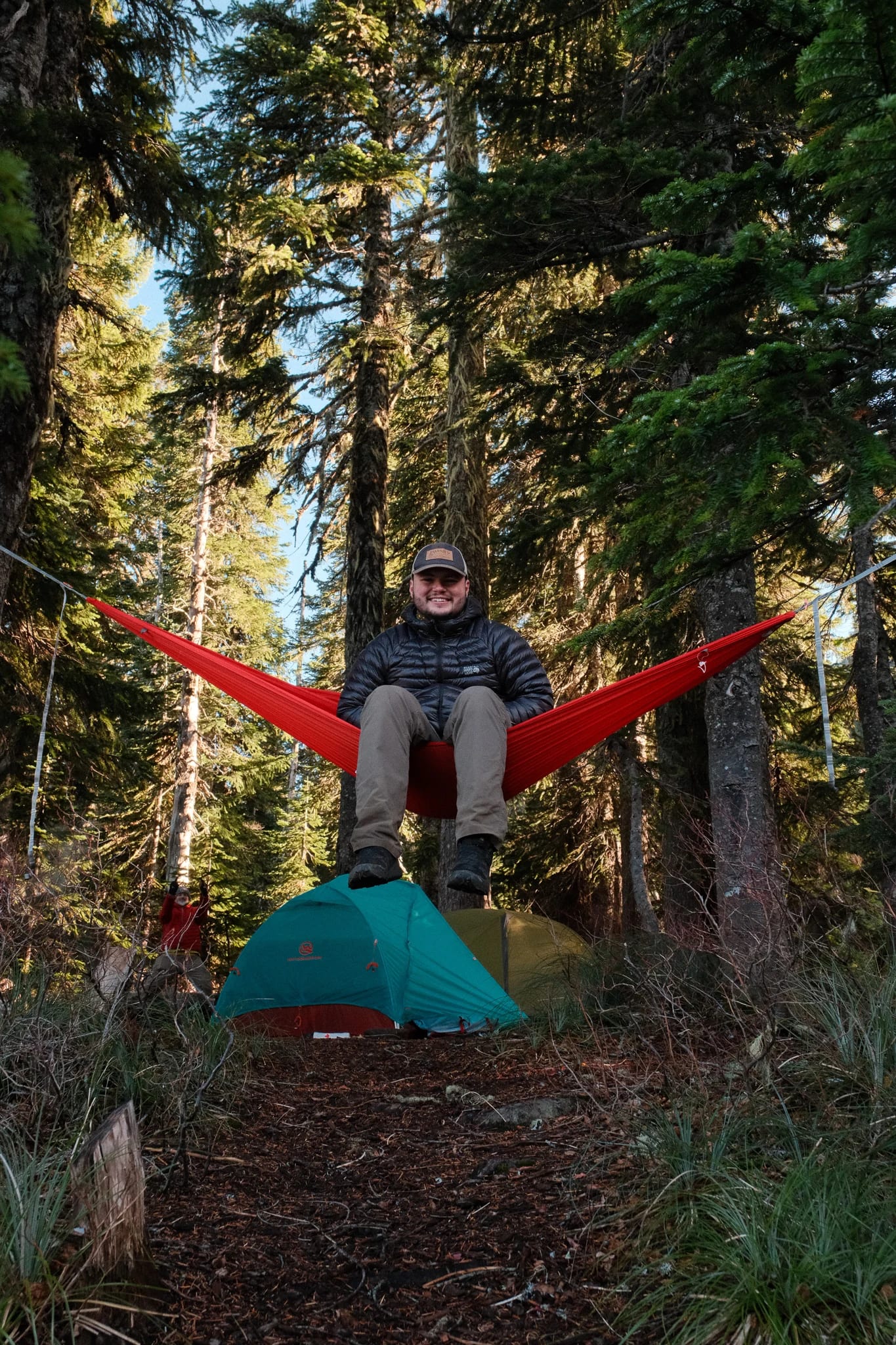 Camper sitting in a Kammok hammock above a WindQuester tent
