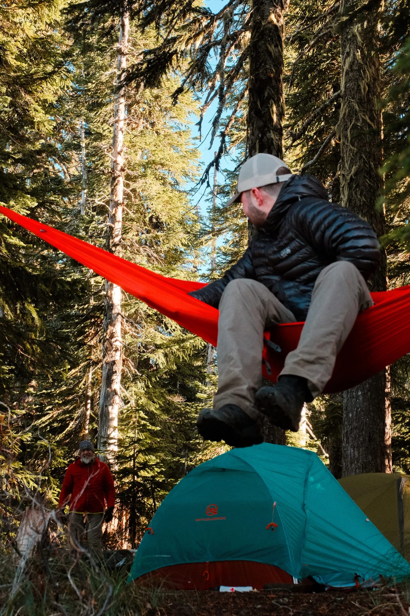 Close view of a camper in a Kammok hammock with a tent below
