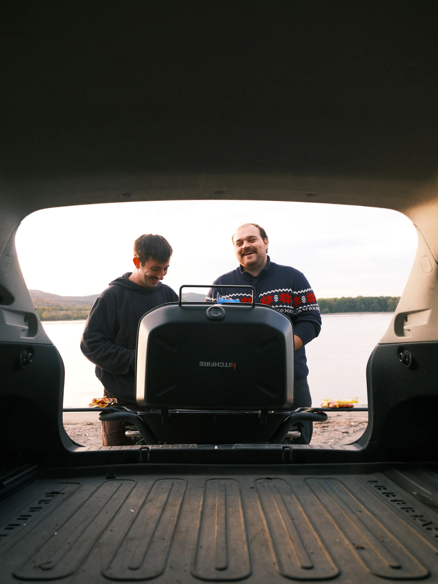 Friends gather behind a car with a mounted grill.