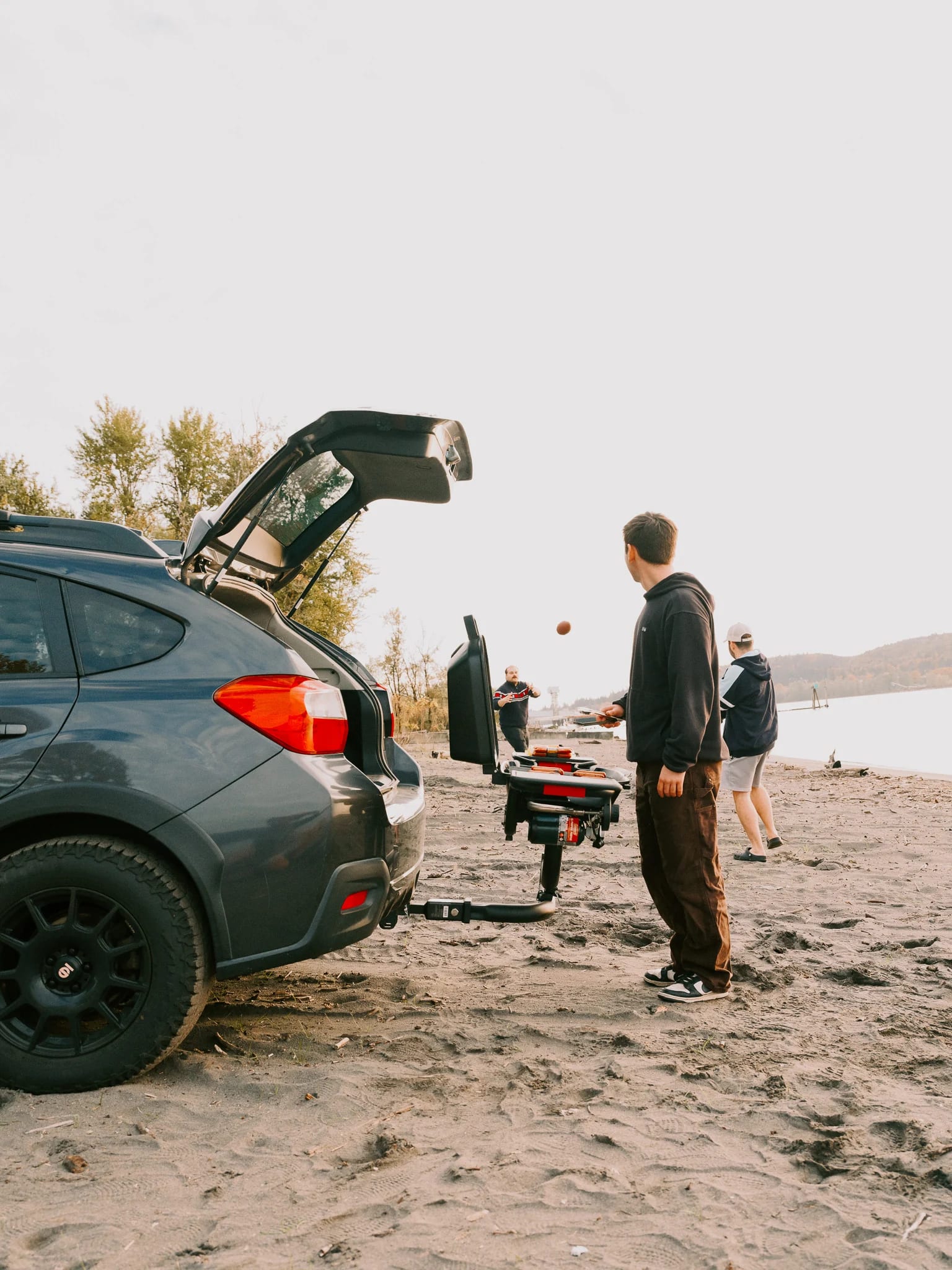 A guest stands beside a vehicle and outdoor grill.