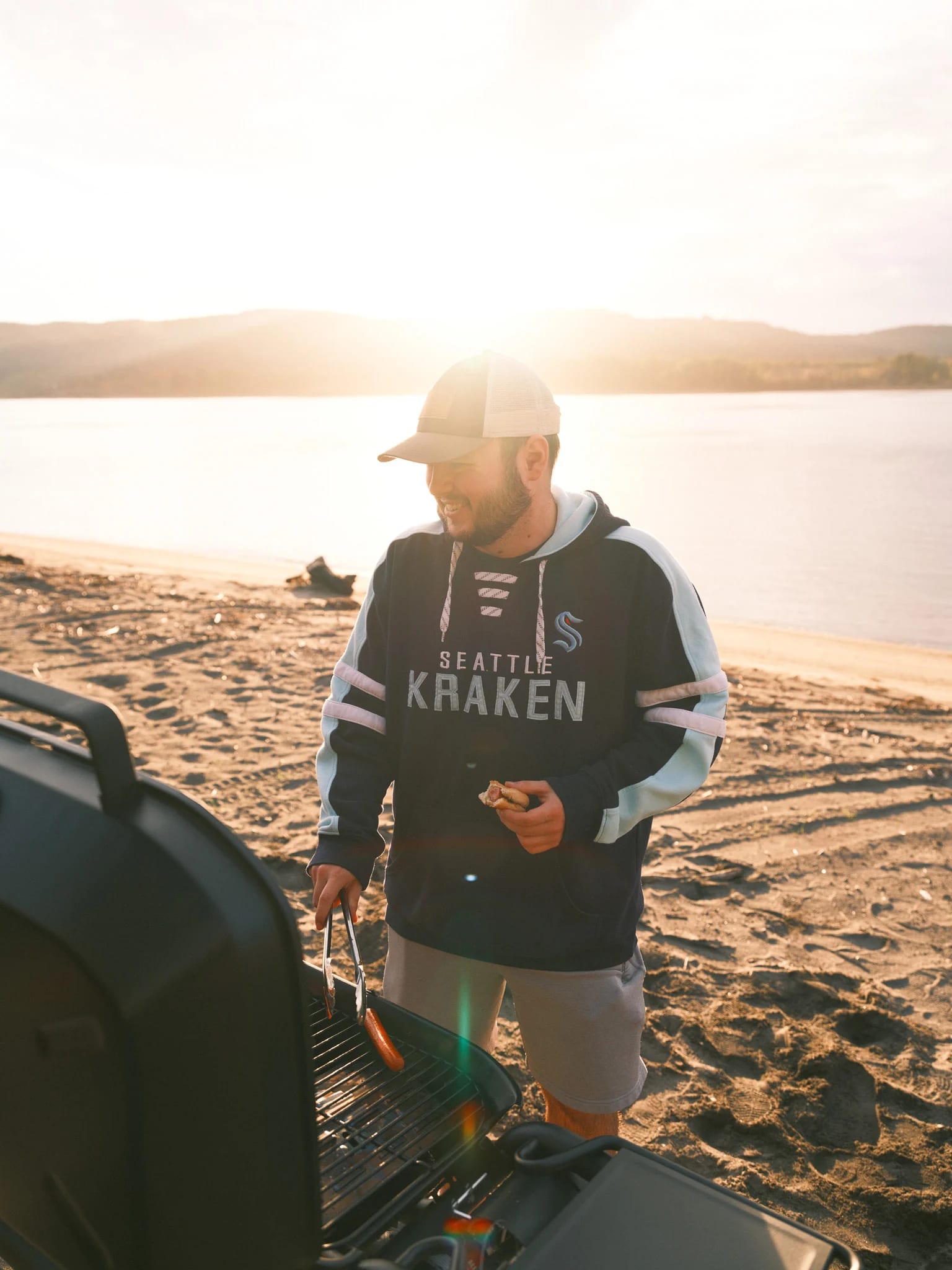 A guest shares a drink beside a lakeside grill.