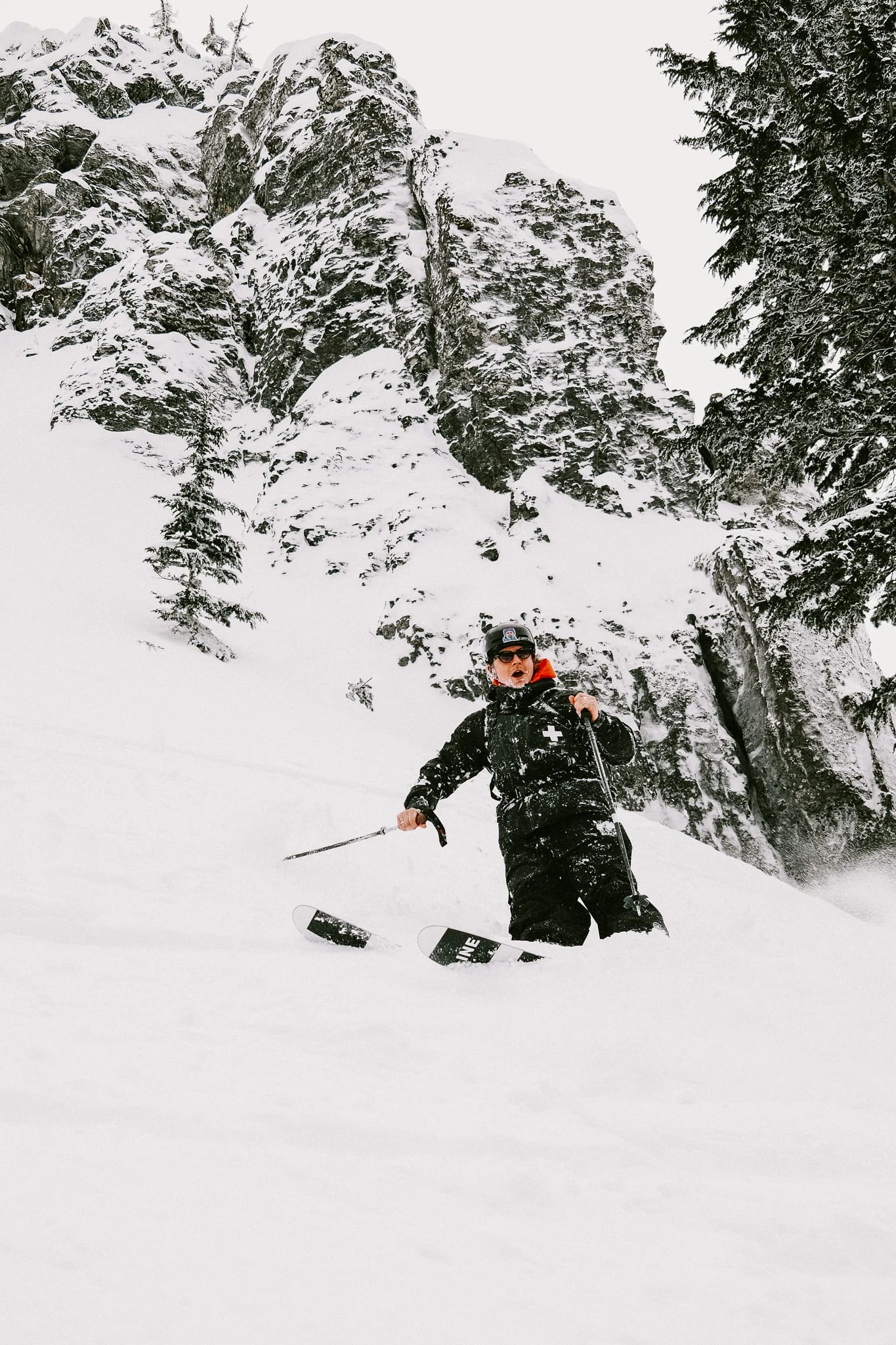 A skier carves between snow-covered trees.