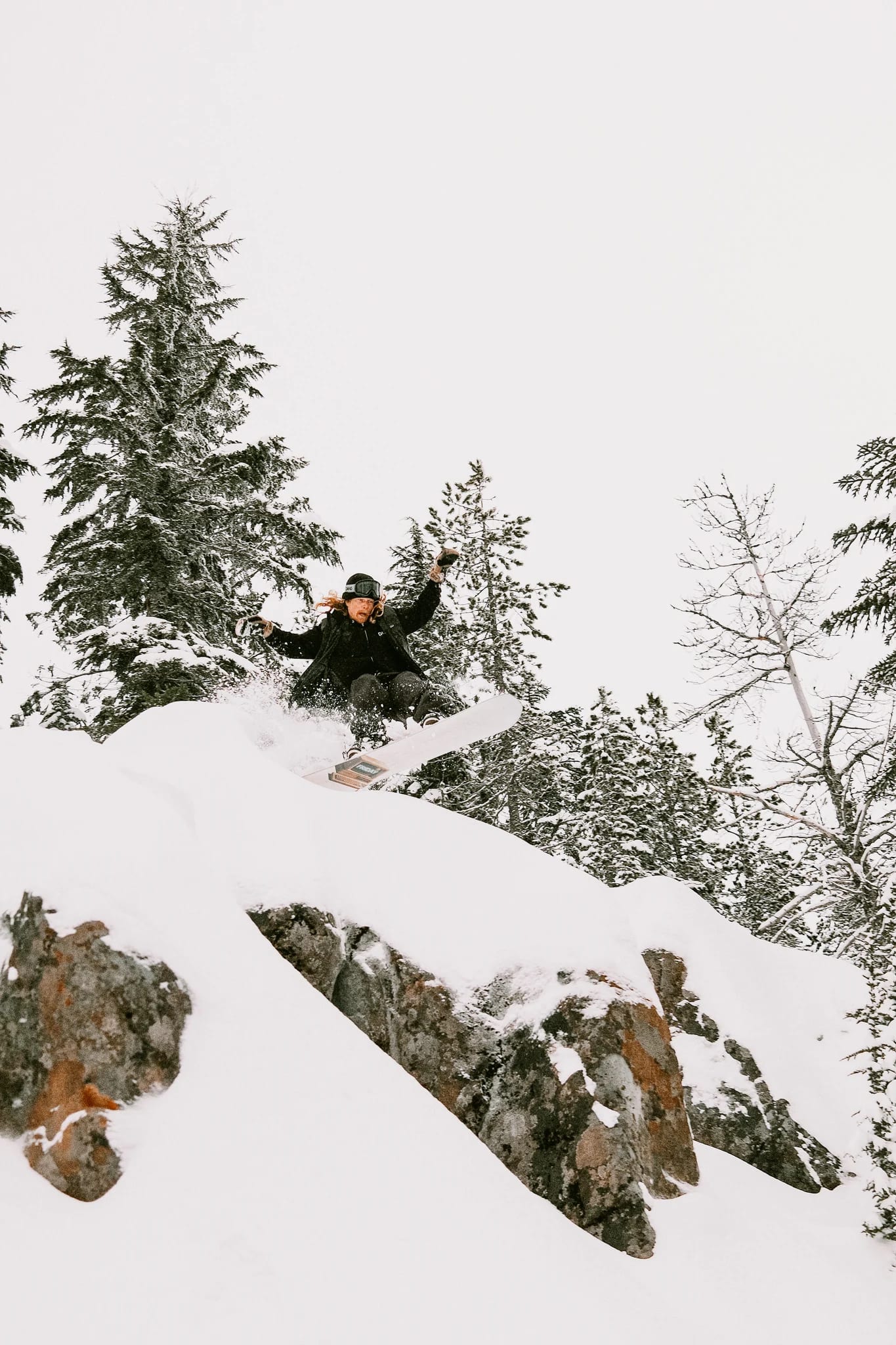 A skier jumps over a snow-covered rock.