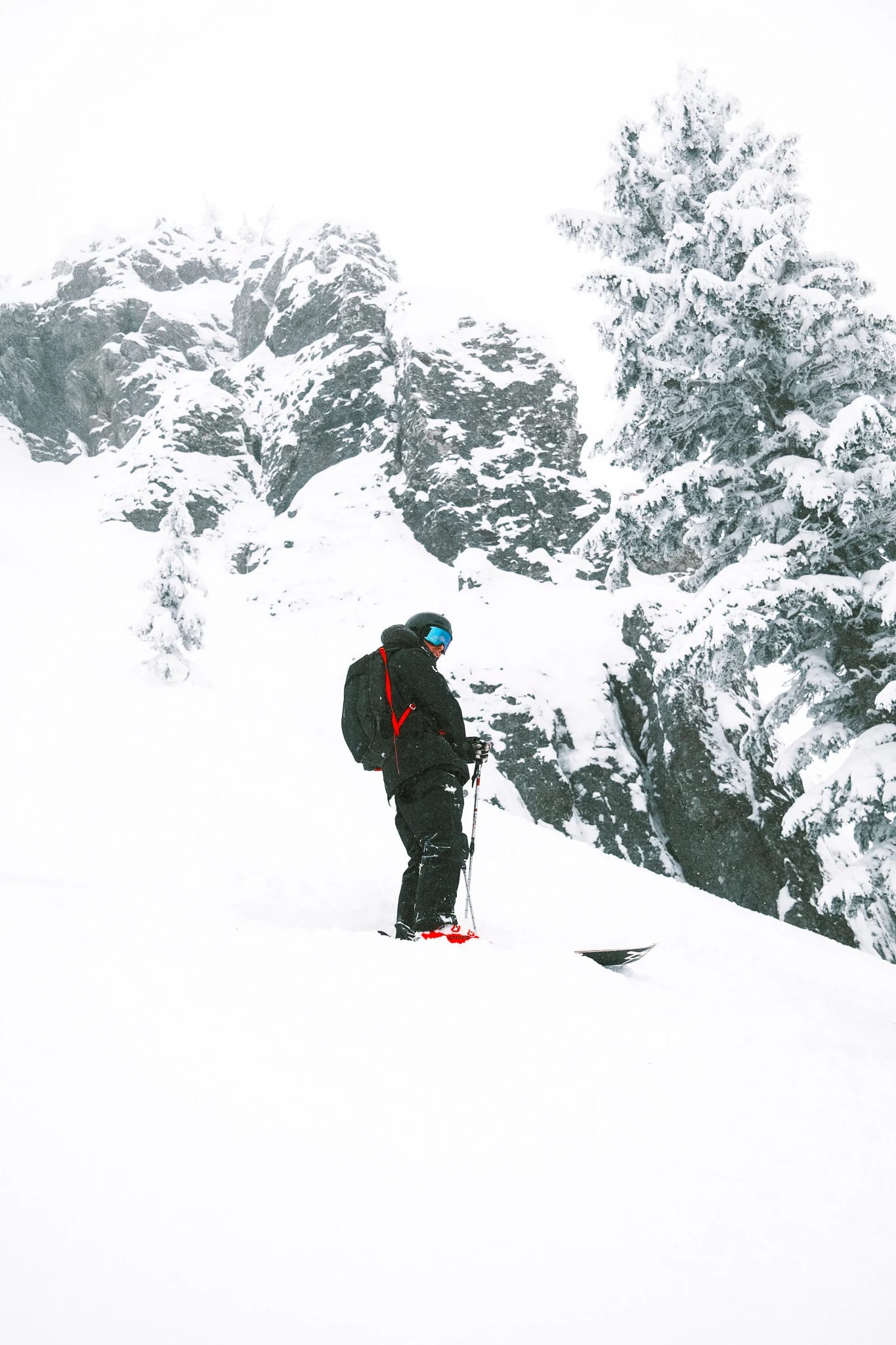 A skier climbs below a dramatic snowy ridge.