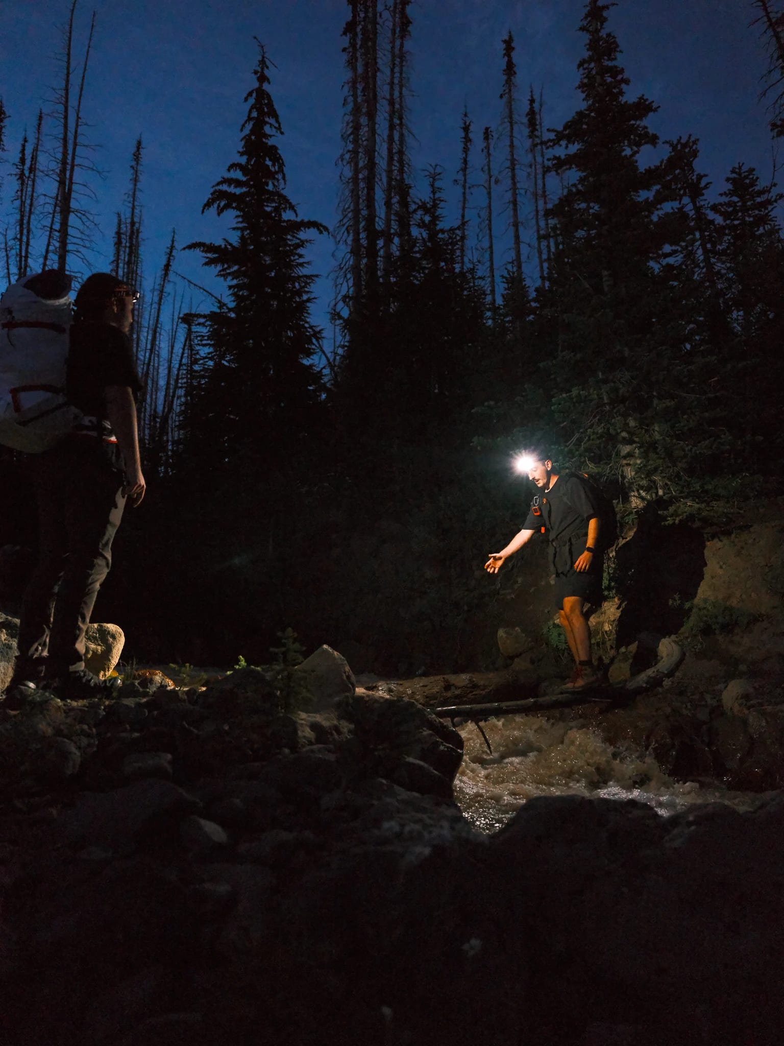 Headlamps illuminate hikers on a rocky trail.