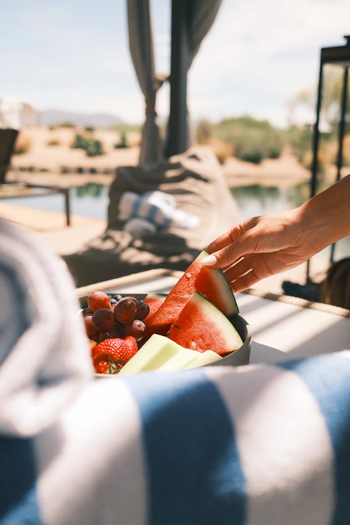 A guest enjoys fruit beside a sunny pool.