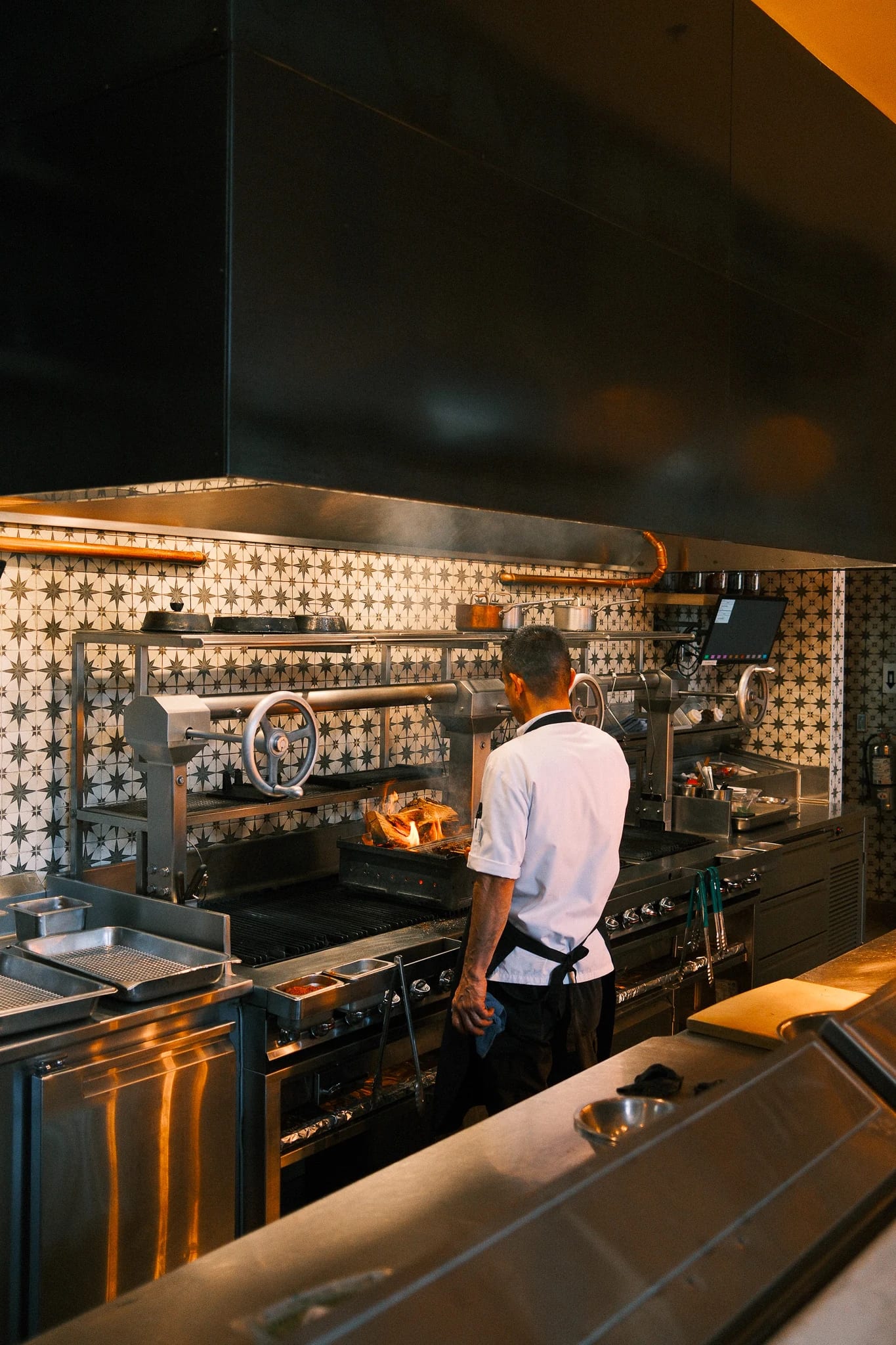 A chef works beside a wood-fired oven.