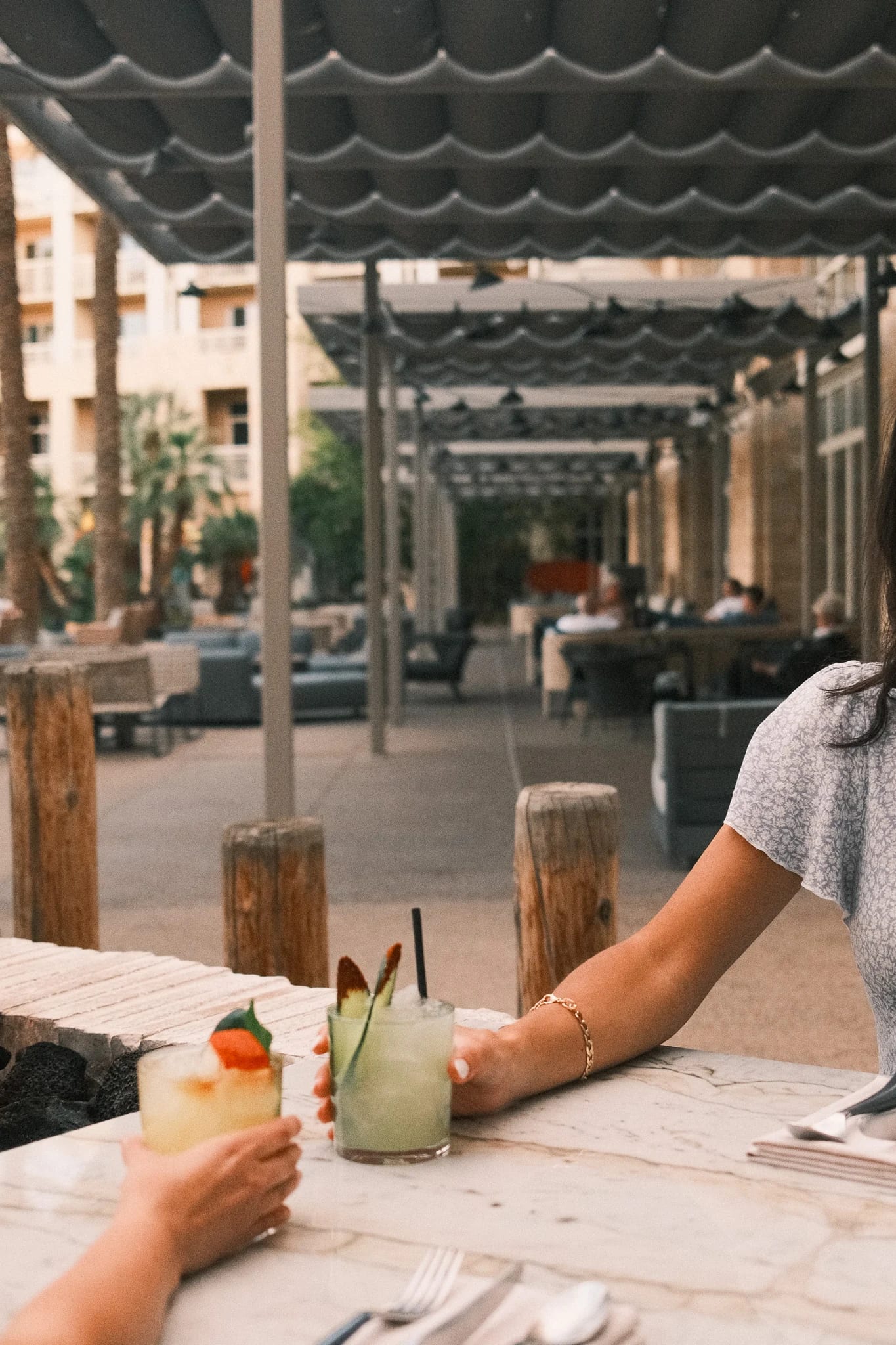 Guests share drinks beneath a shaded terrace.