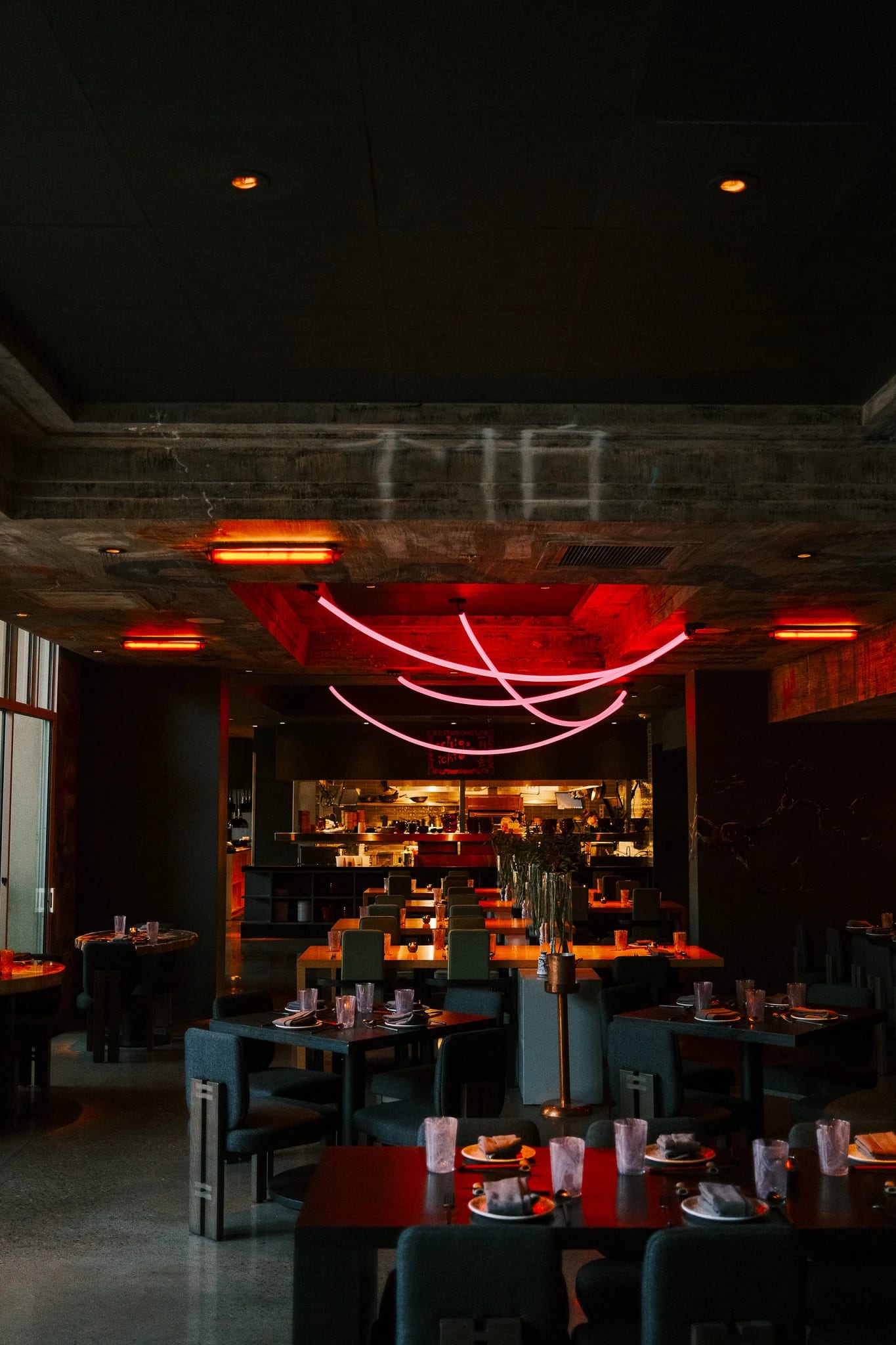 Red pendant lights above a dark restaurant lounge.