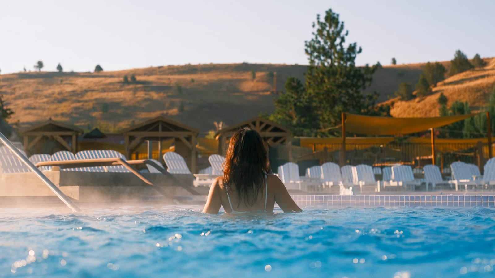 A guest relaxes in a steaming blue pool.