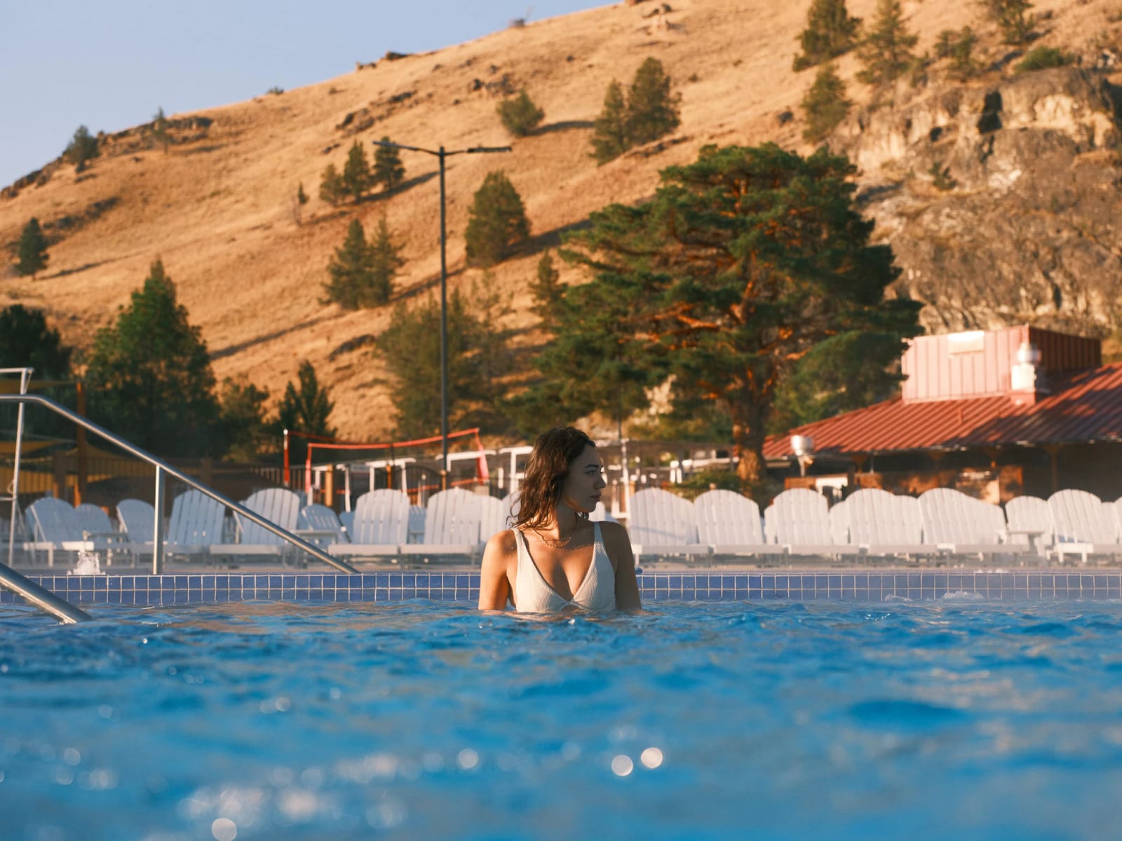A guest in a blue pool beneath golden hills.