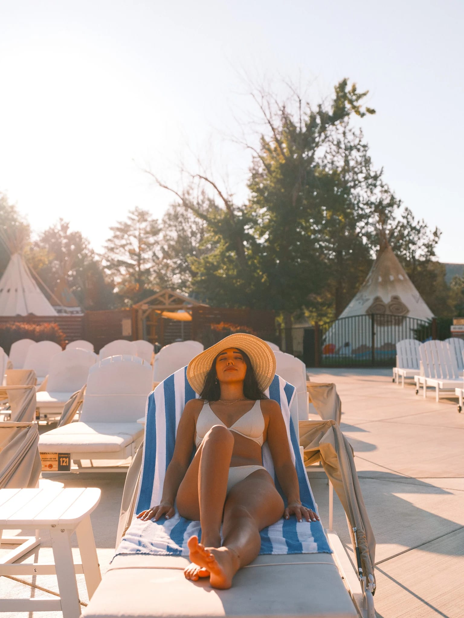 A guest rests on a sunlit pool lounger.