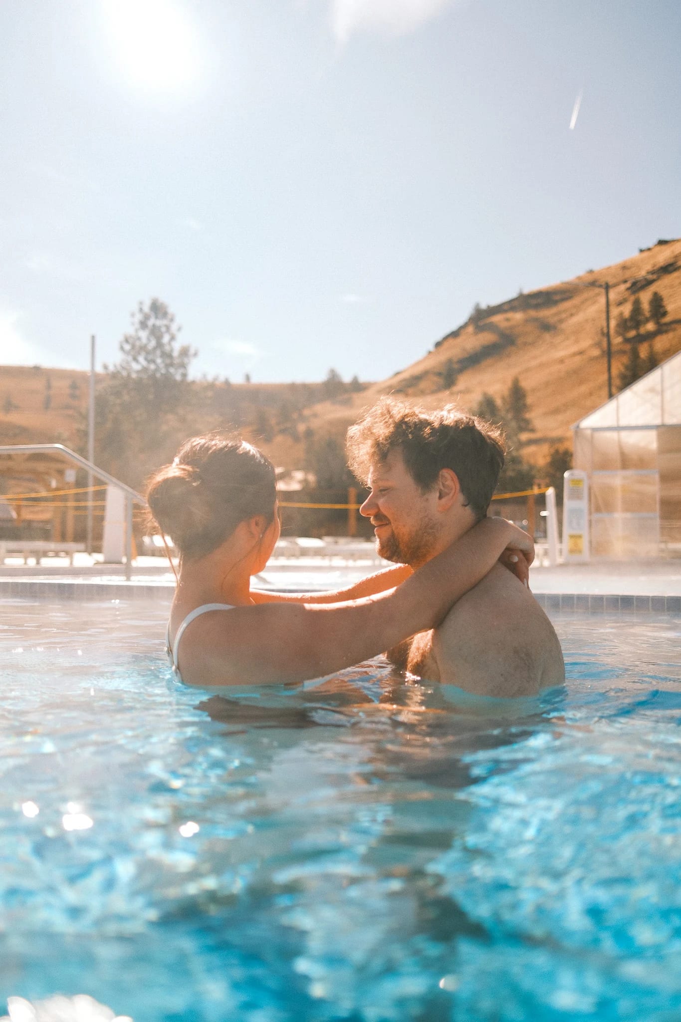 A parent lifts a child in a steaming pool.