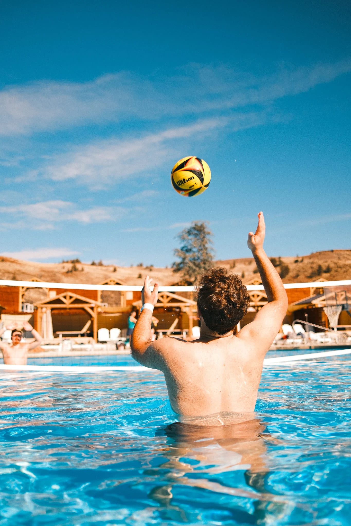 A guest plays ball in a bright blue swimming pool.
