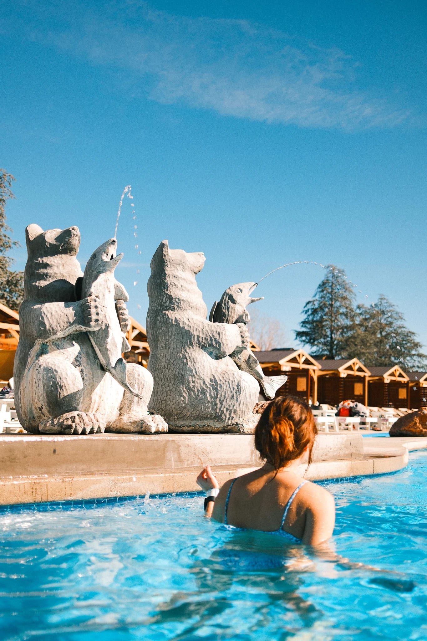 A guest enjoys the pool beside sculptural water features.