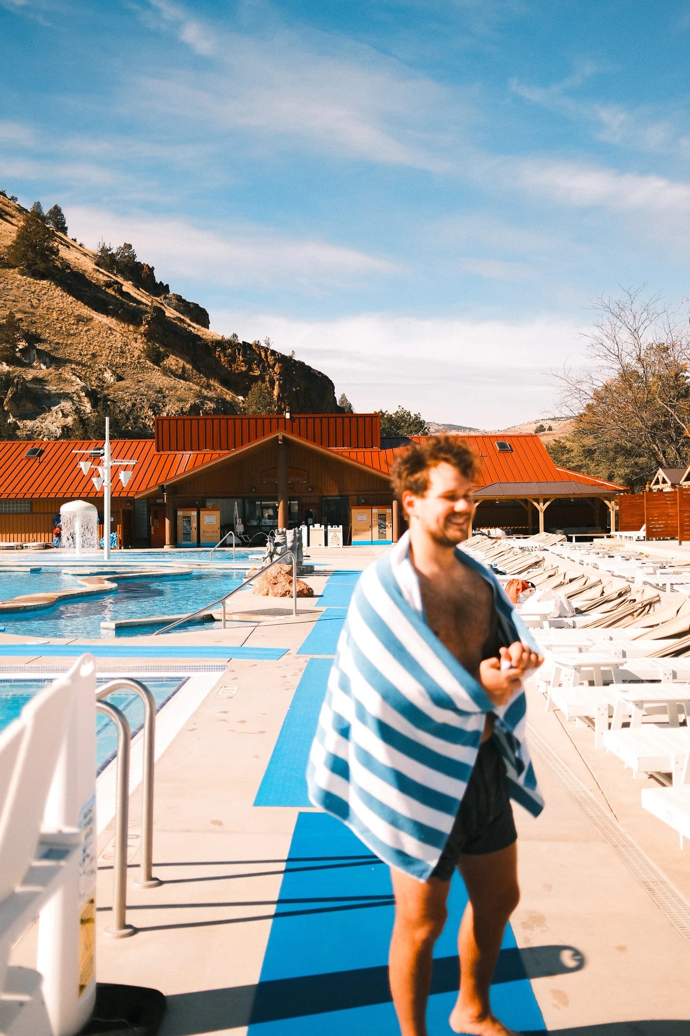 A guest in a striped towel walks past the pool.