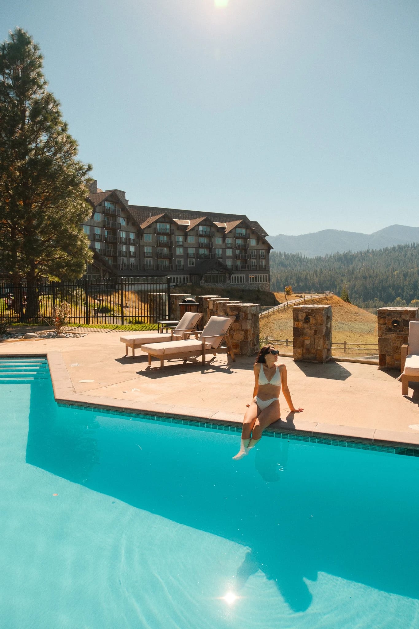 Guest beside the turquoise pool with the lodge behind