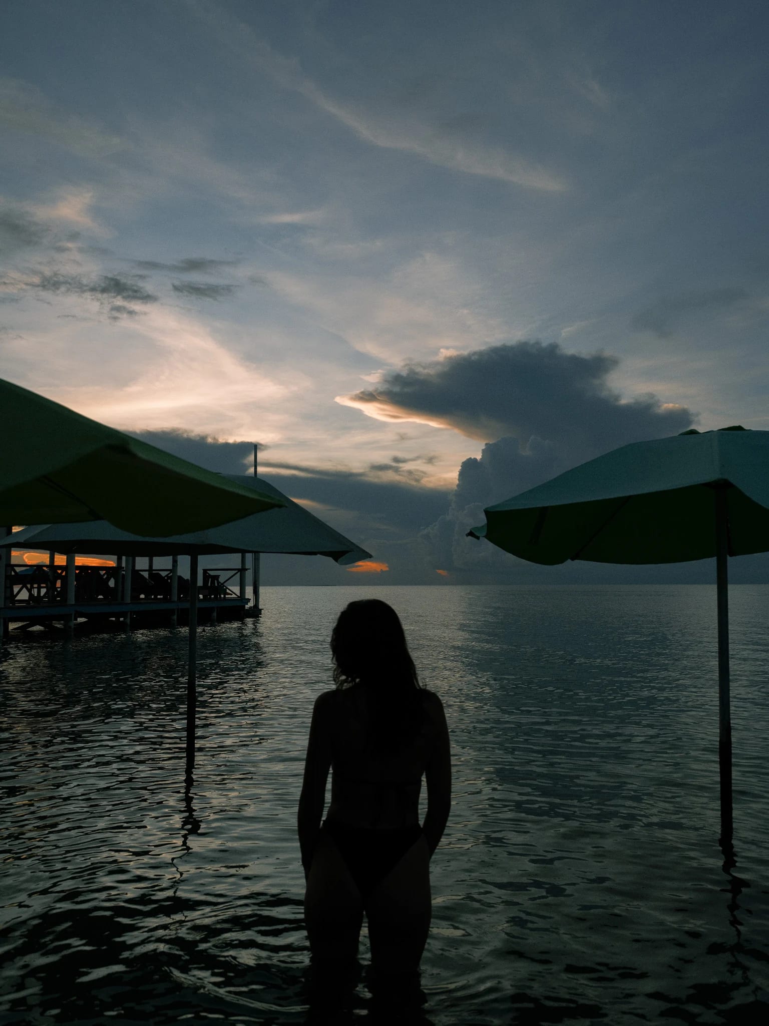 A guest stands beside still water at sunset.
