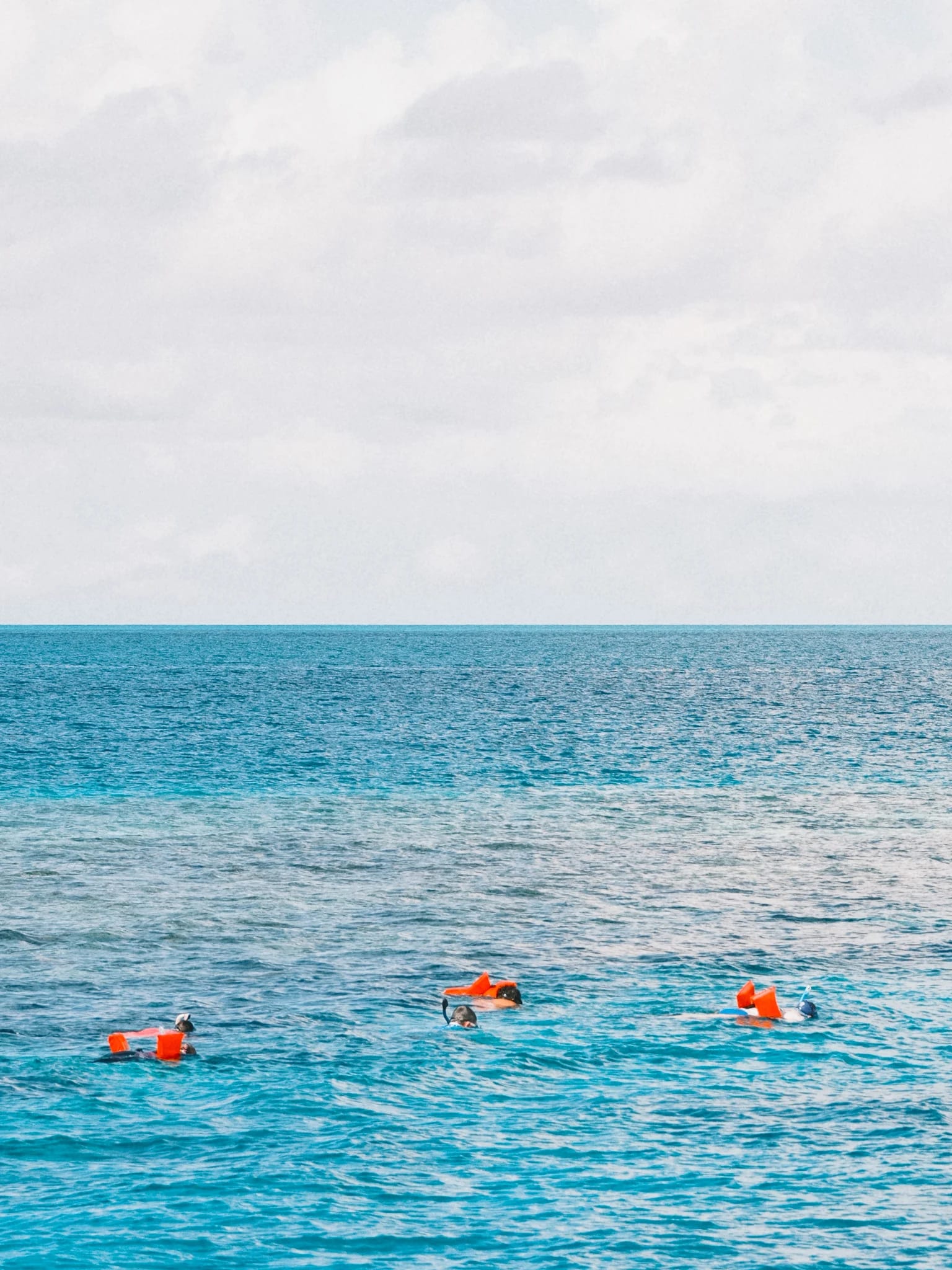Snorkellers float in clear turquoise water.